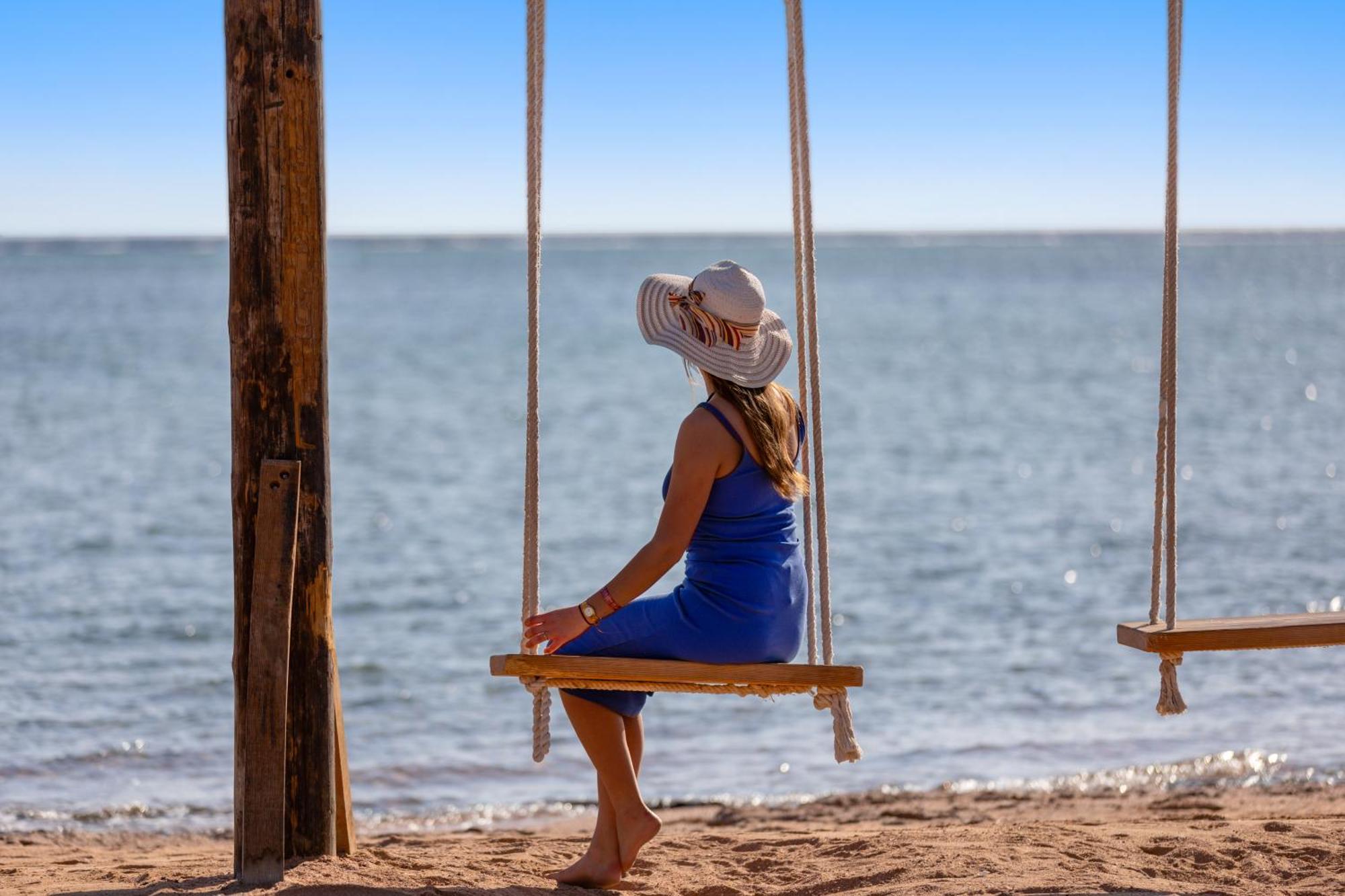 Pickalbatros Royal Moderna Sharm "Aqua Park" Hotel Exterior photo A woman on a swing at the beach